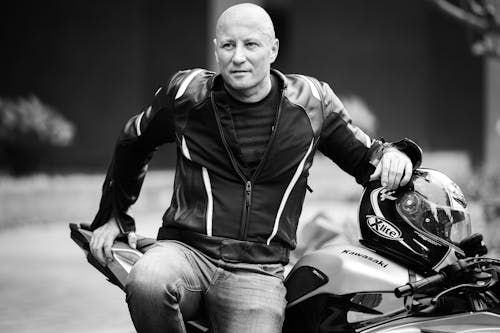 Free Monochrome Photo of a Man in a Leather Jacket Sitting on His Motorcycle Stock Photo