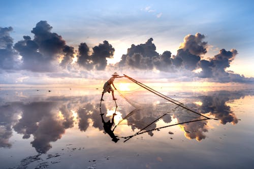 Man Throwing a Fishing Net in Sea at Dusk 