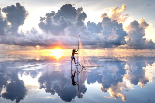 Man Throwing a Fishing Net in Sea at Dusk 