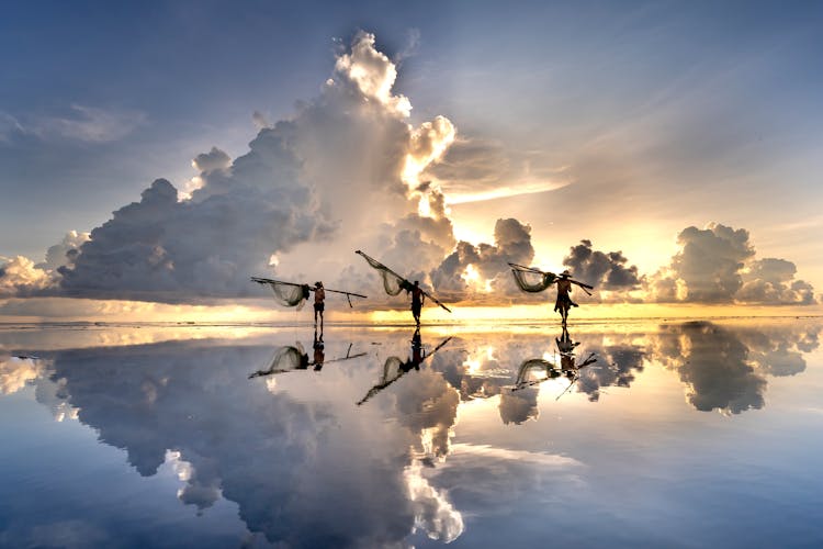 Men Throwing Fishing Nets In Sea At Dusk In Vietnam 