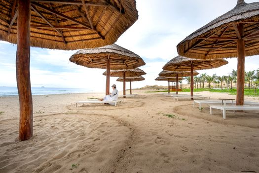 Relaxing beach scene with straw umbrellas and a clear sky, perfect for a peaceful getaway.