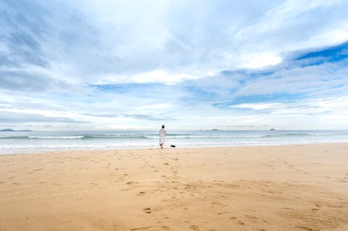 Free A Woman in White Dress Standing on Beach Stock Photo