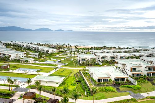 Free Aerial view of a modern beachfront resort, showcasing villas and lush green landscapes. Stock Photo