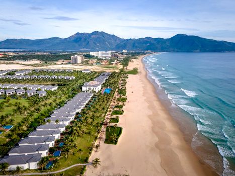 A stunning aerial view of beachfront resorts, sandy shores and blue ocean waves.