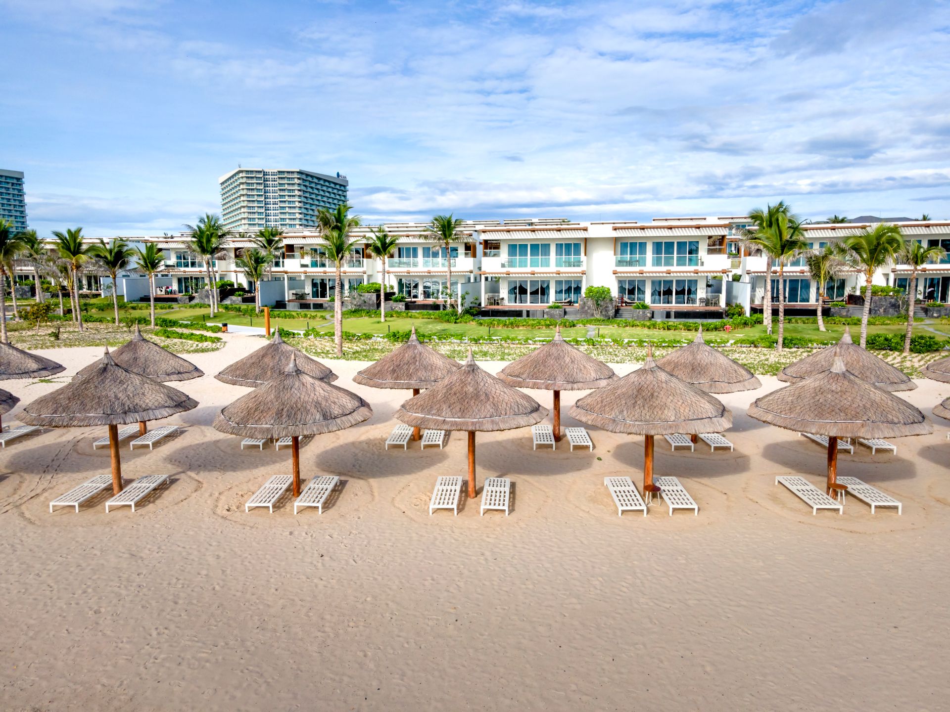 A serene beachside view with straw umbrellas and a luxury resort backdrop.