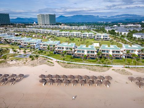 Aerial view showcasing a sprawling luxury beachfront resort with villas and palm-lined shore in Vietnam.