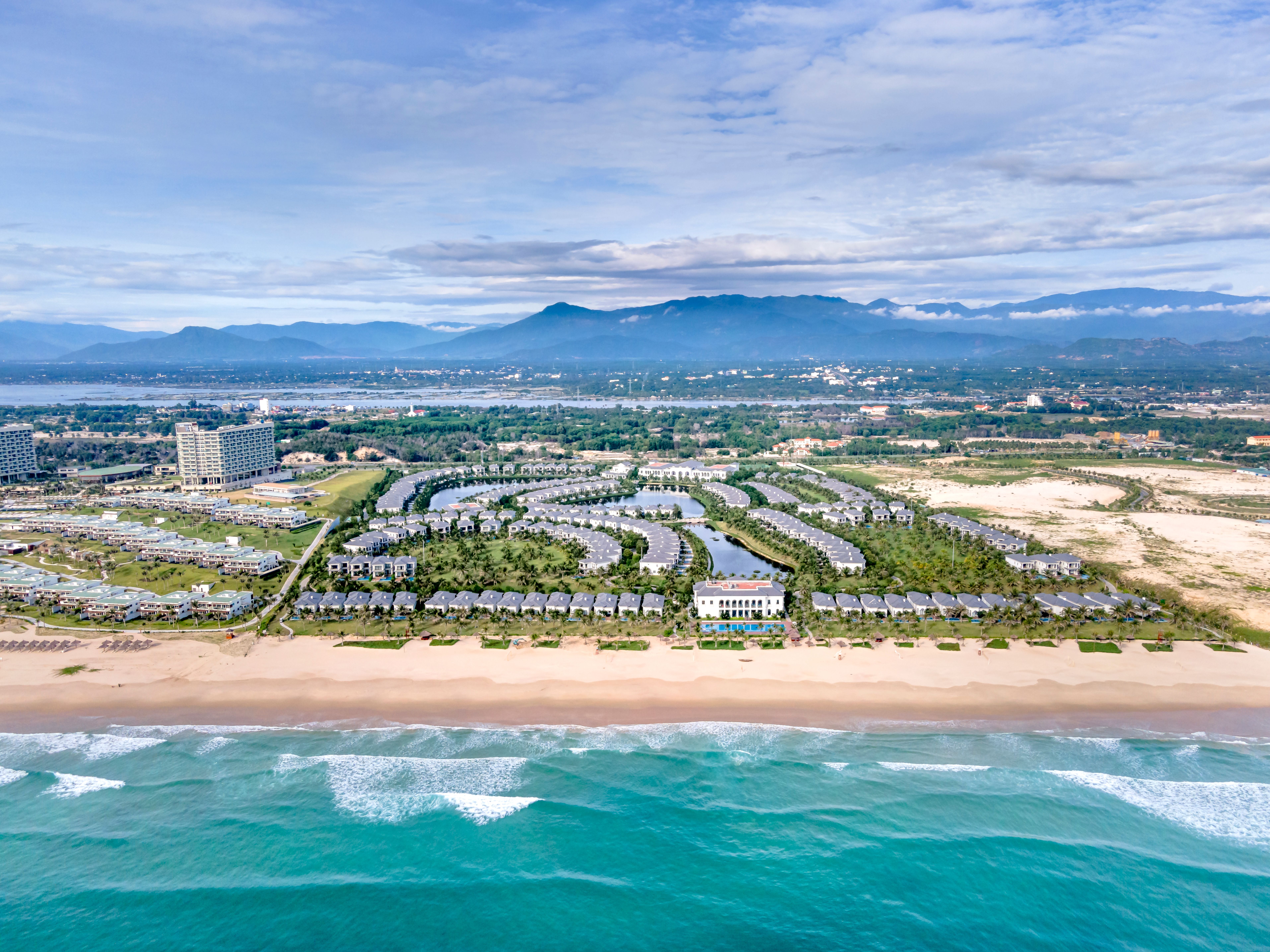 Stunning aerial view of a luxurious resort along the Vietnam coastline with turquoise sea and sandy beach.