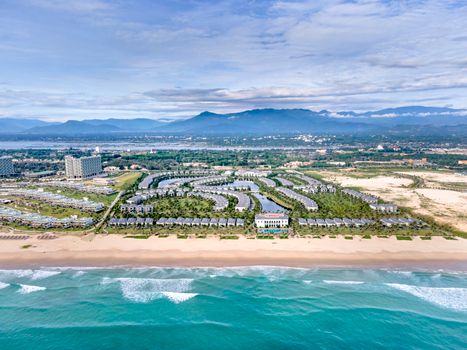 Stunning aerial view of a luxurious resort along the Vietnam coastline with turquoise sea and sandy beach.