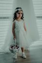 A Beautiful Kid Wearing White Dress and Flower Headdress Carrying a White Basket