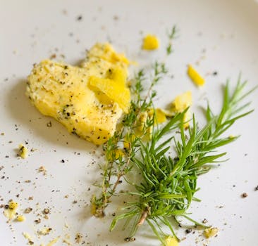 Close-up of delicious herb-infused cheese with fresh rosemary and lemon zest on a white plate.