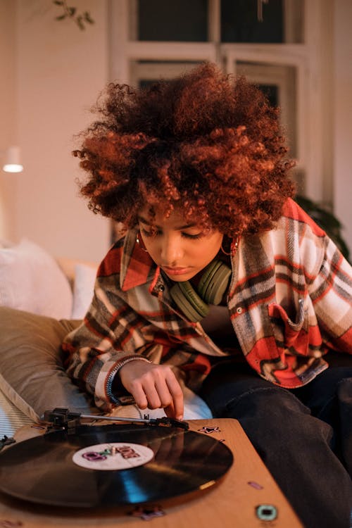 Photo of a Woman with Curly Hair Listening to Music