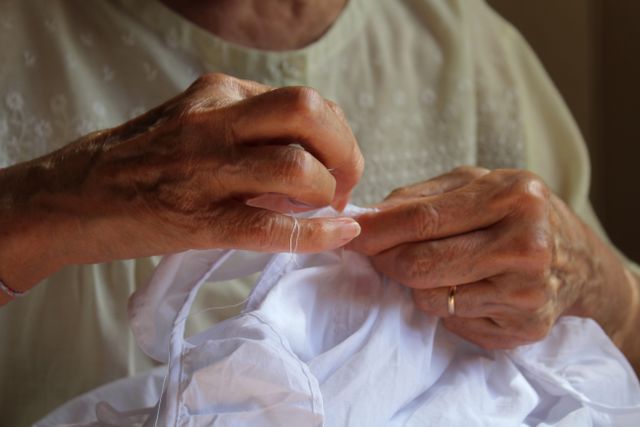 Hands hand-sewing white fabric, photo by Sara Puig Sanz on Pexels