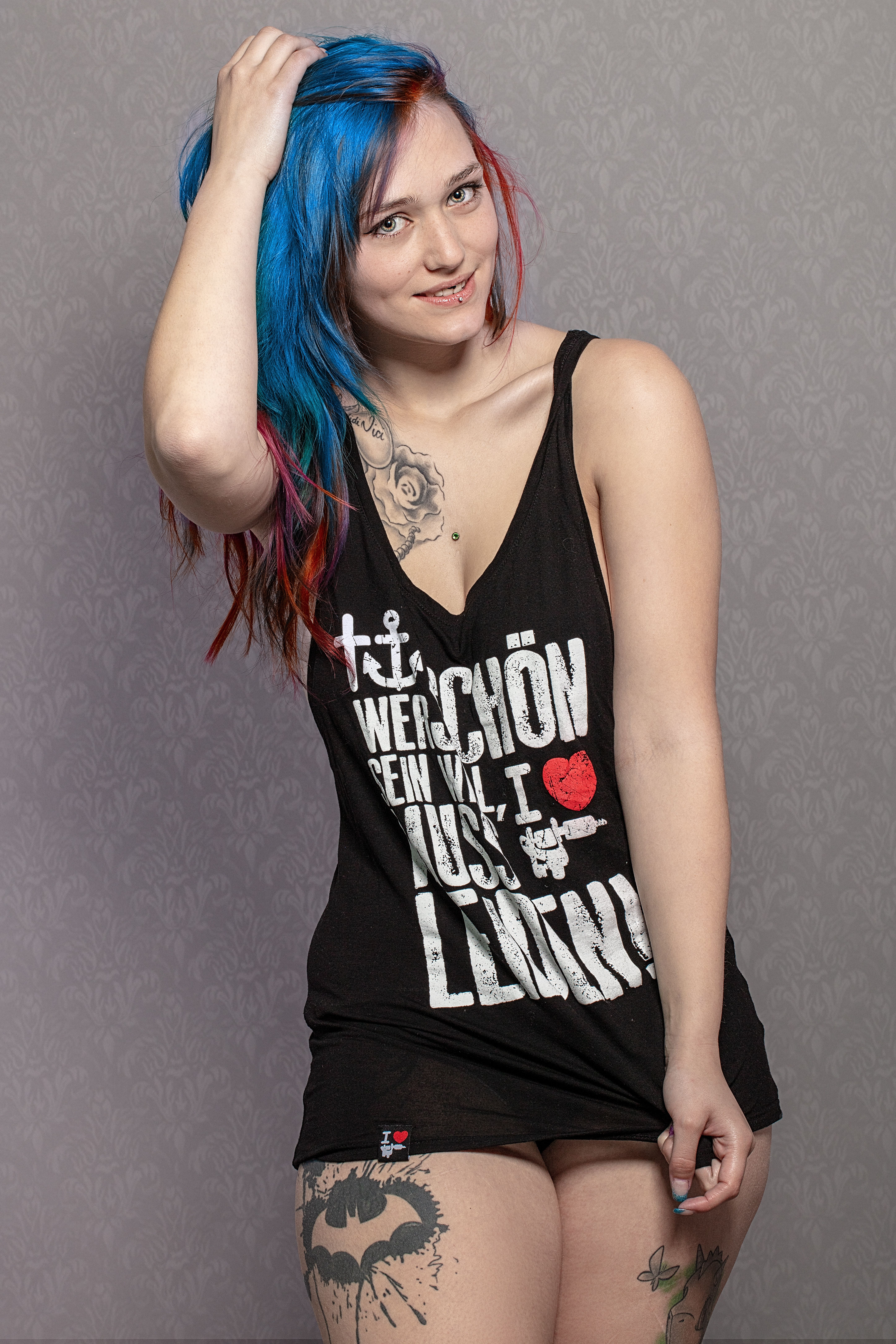 Vibrant studio portrait of a tattooed woman with striking blue hair posing confidently.