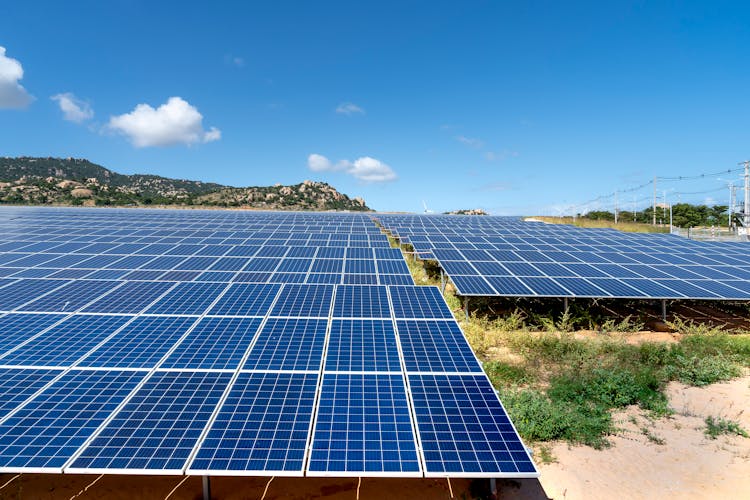 Solar Panels On Field And Blue Sky