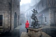 Man in Red Hoodie Standing on Black Statue