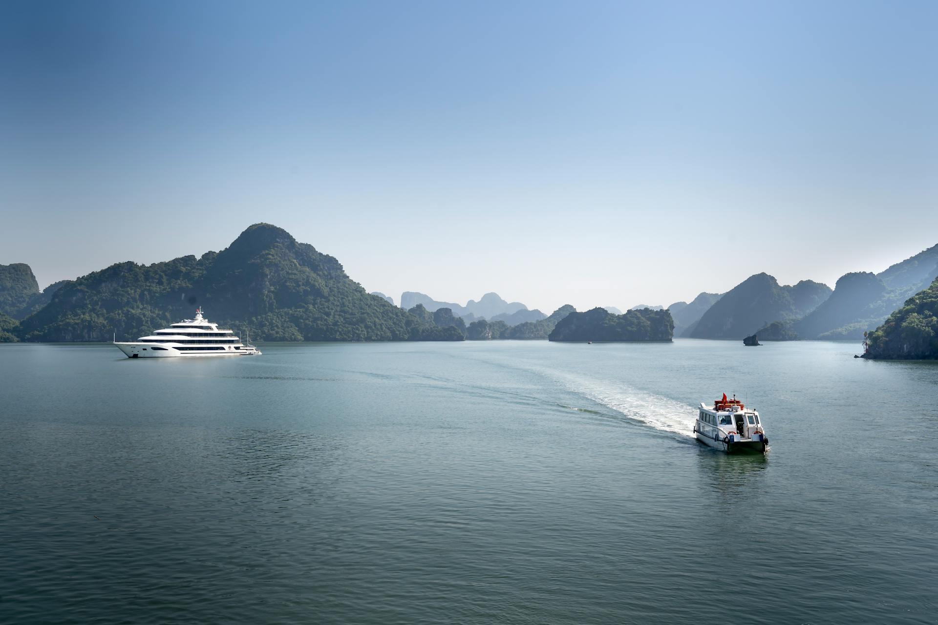 Explore serene island waters with a luxury yacht and boat in a picturesque natural setting.