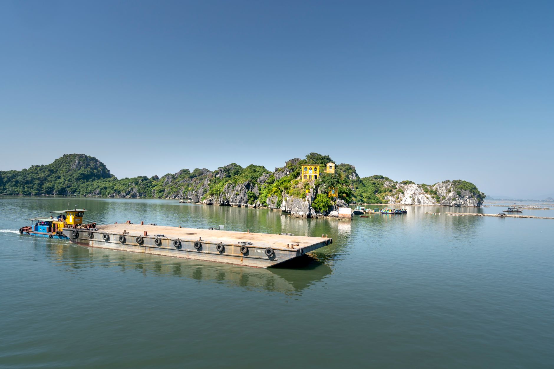 A boat sails near a rocky island with lush greenery in Quang Ninh Province, Vietnam.