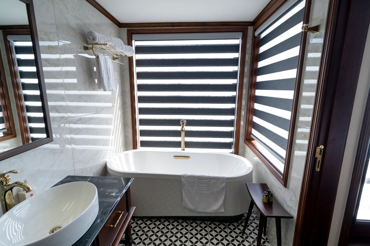 Bright bathroom with a freestanding white bathtub under large windows