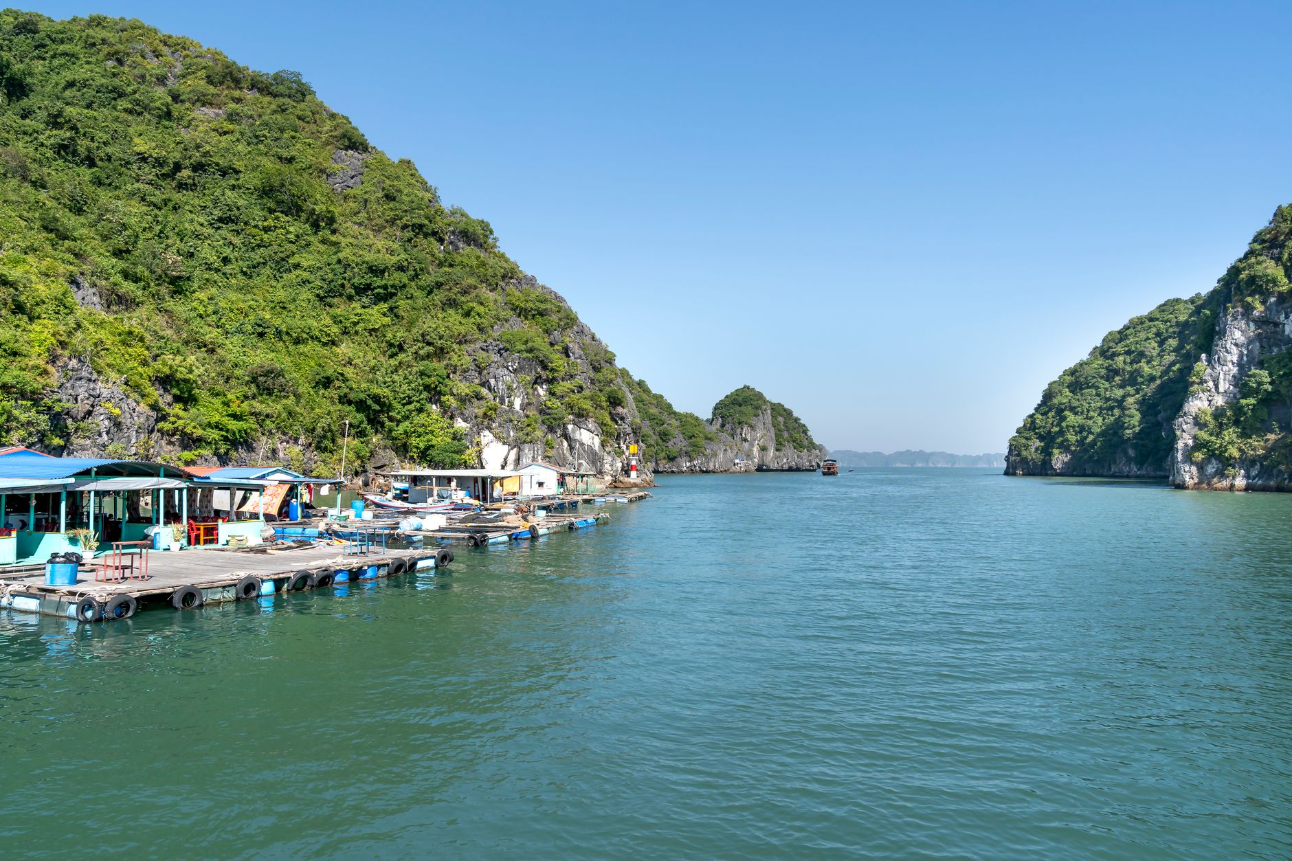 A tranquil fishing village along a vibrant coastline surrounded by lush greenery under a clear blue sky.