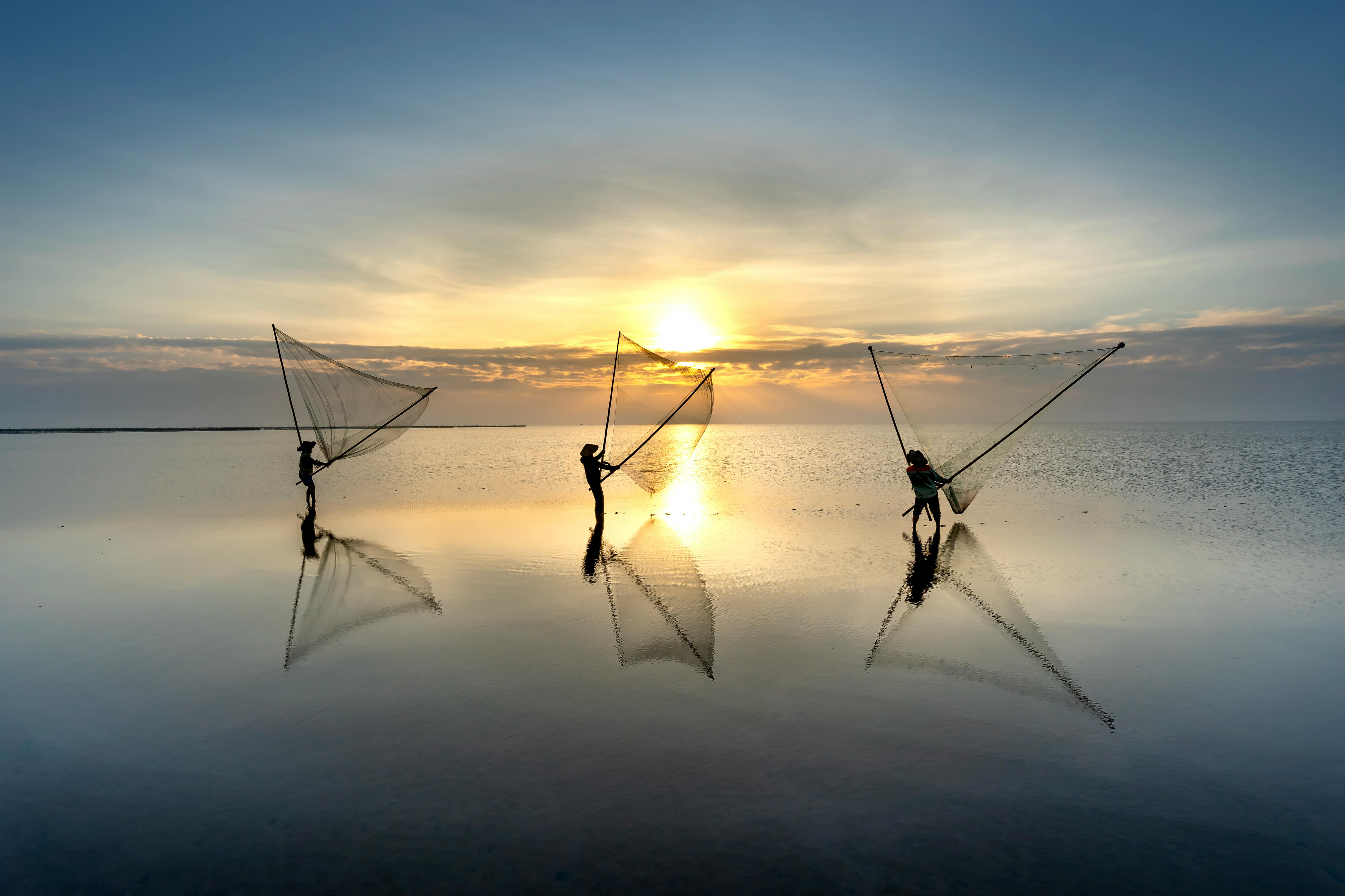 Men Throwing Fishing Nets in Sea at Dusk in Vietnam · Free Stock Photo