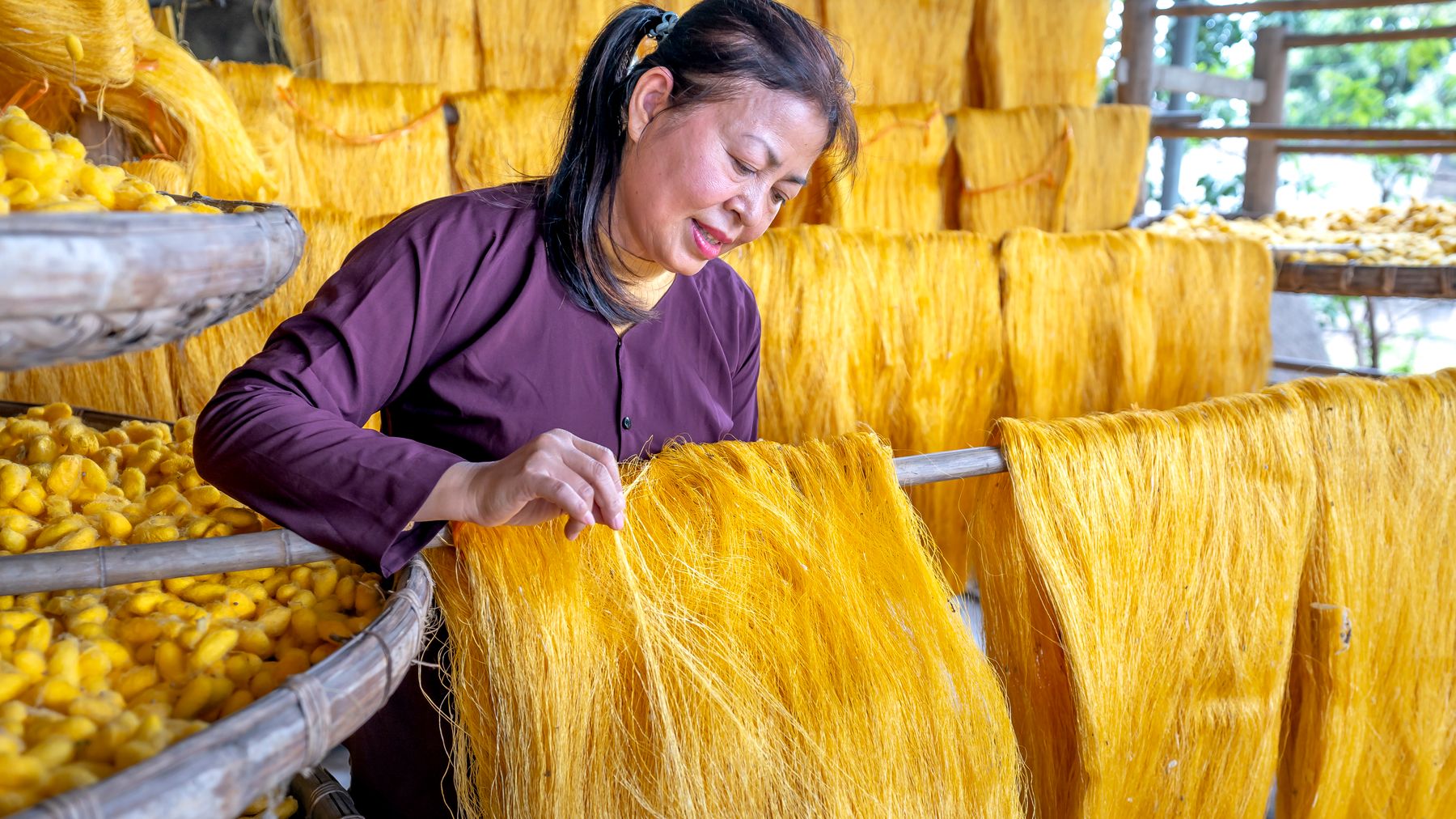 Woman working with silk threads in traditional Vietnamese silk village.
