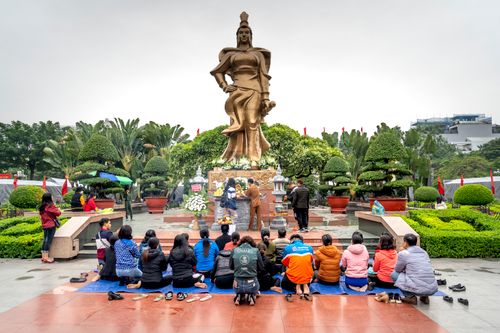 Free A group of people kneeling and praying in front of a large monument outdoors. Stock Photo