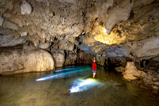 A person explores a fascinating limestone cave, illuminated by natural light.