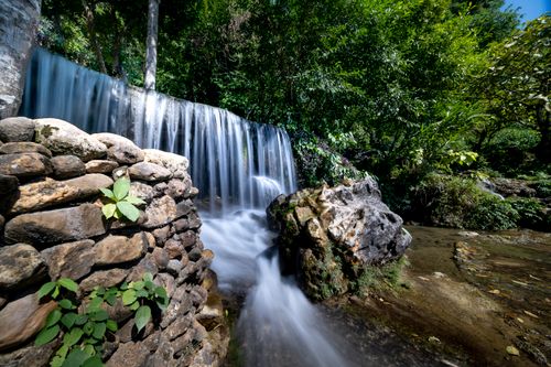 Free Tranquil waterfall cascading over rocks surrounded by lush forest. Stock Photo