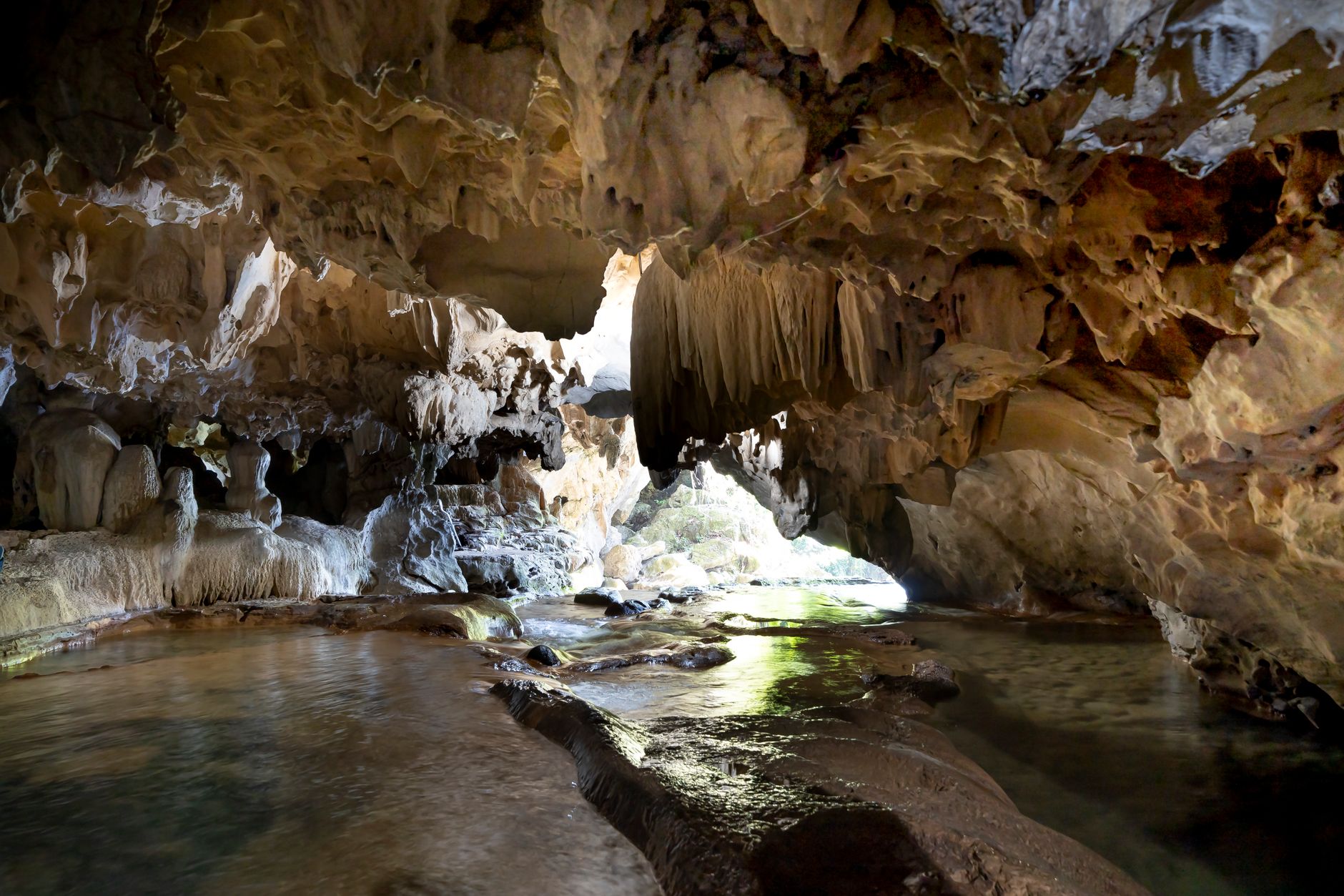 Explore a breathtaking cave with intricate rock formations and flowing water.