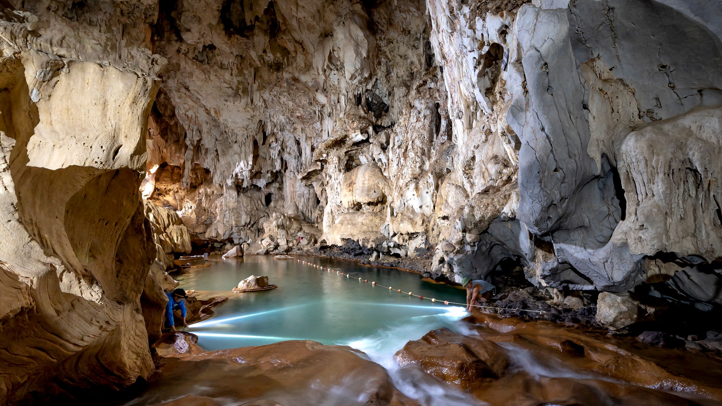 Explore the breathtaking beauty of a limestone cave featuring a crystal-clear lake with stunning stalactites.