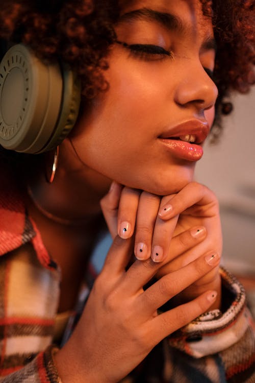 Close-Up Photograph of a Woman with Curly Hair Listening to Music