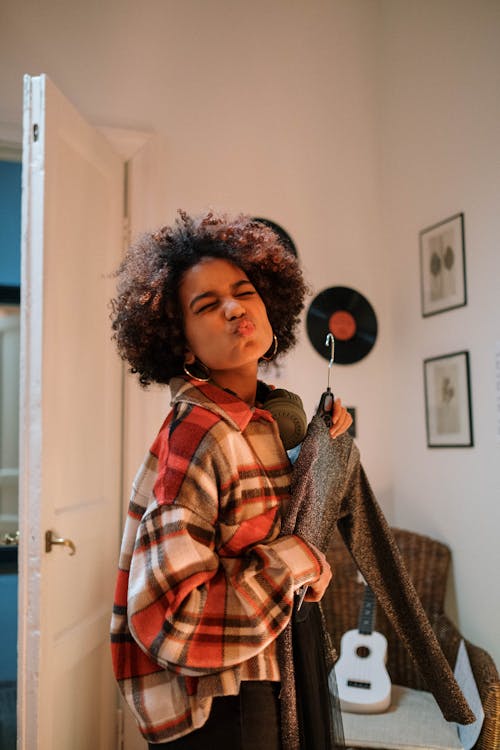 Woman in Plaid Shirt Holding a Long Sleeve Shirt with Hanger