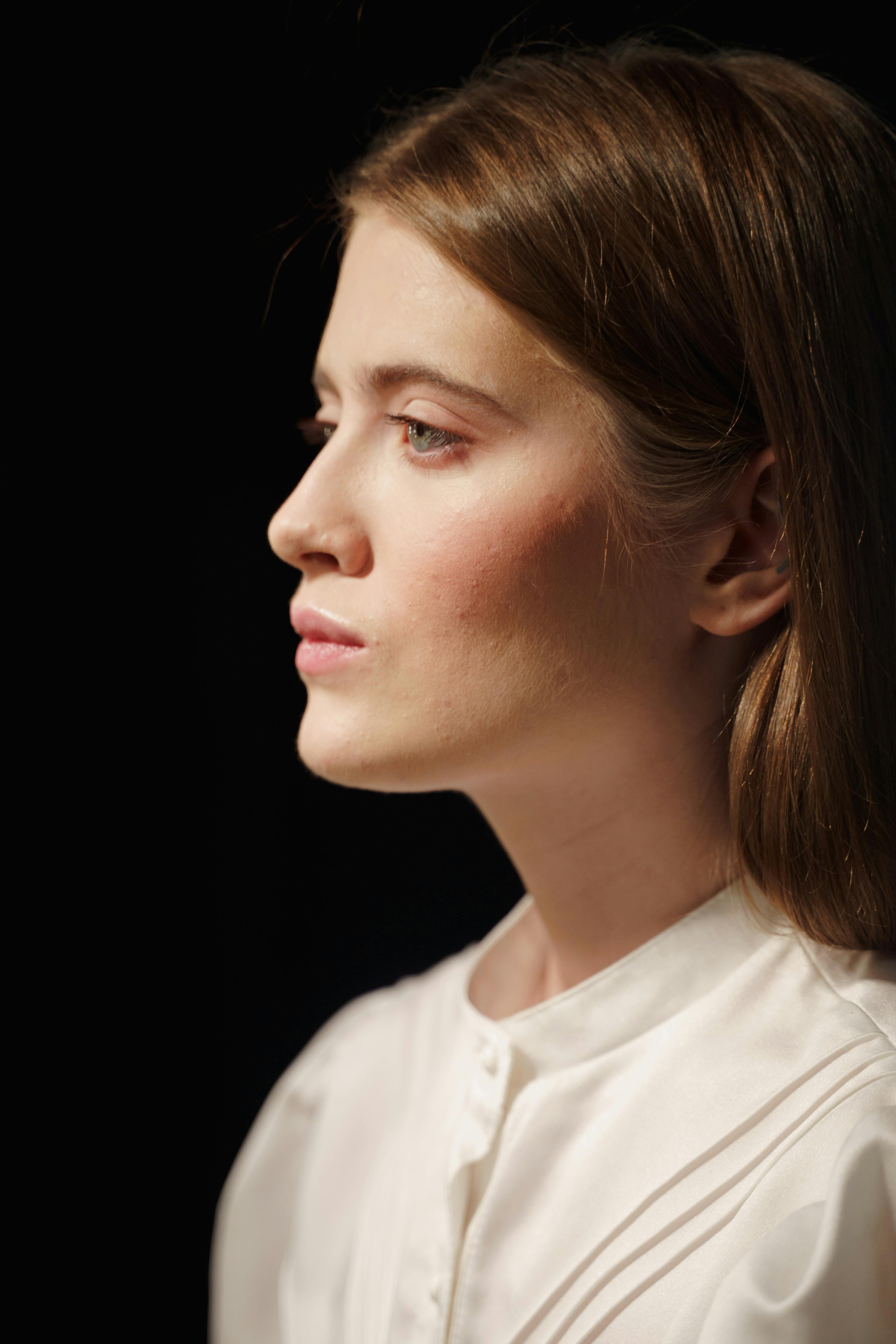 A striking portrait of a young woman in elegant fashion against a black background.