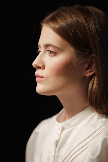 A striking portrait of a young woman in elegant fashion against a black background.