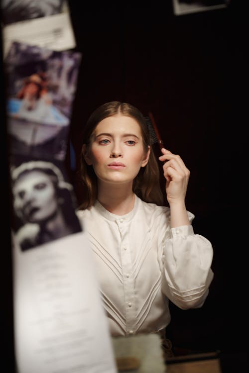 Woman in White Long Sleeve Shirt Applying Makeup