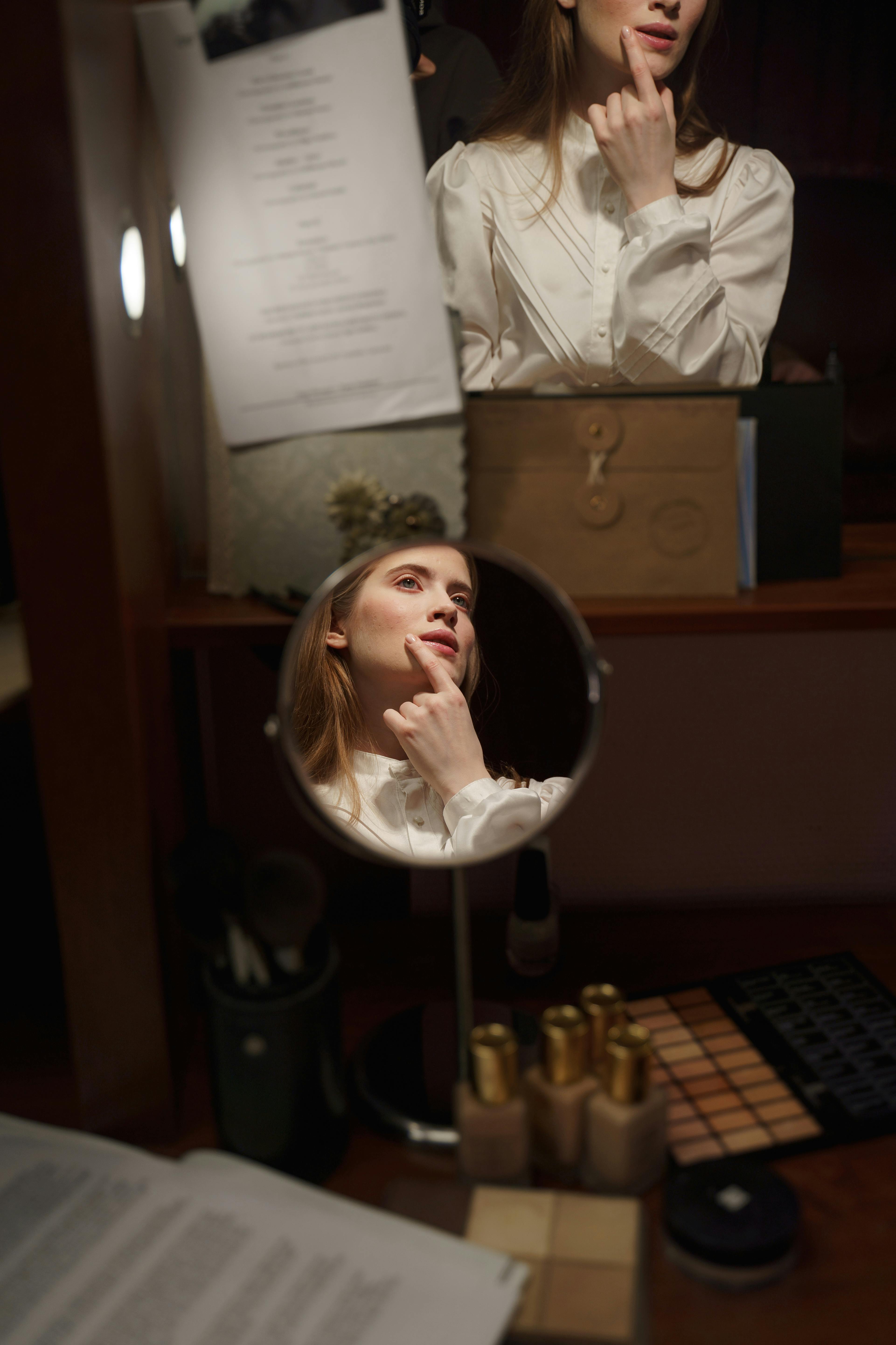 reflection of woman in white long sleeve shirt sitting on chair