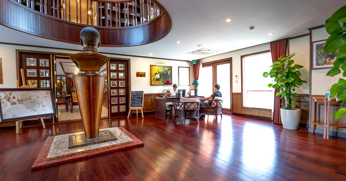 Elegant interior of a cruise ship with a wooden statue, seating area, and decor.
