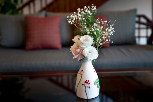 Free Artistic floral arrangement with roses and baby's breath in a vase on a table. Stock Photo