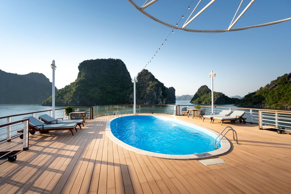 Luxury resort in Ha Long Bay Vietnam with infinity pool facing the sea, modern architecture, elegant sun loungers, tropical landscaping, summer afternoon light, ultra realistic, premium hospitality scene