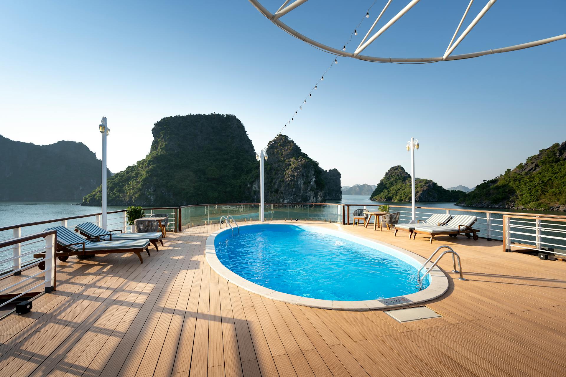 Relaxing cruise ship deck with pool overlooking Ha Long Bay's scenic limestone islands.