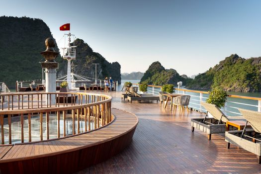 Elegant yacht deck with lounge chairs overlooking a stunning bay and lush islands.
