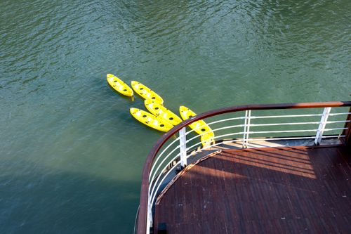 Free Yellow kayaks float beside a ship deck in a serene sea view. Stock Photo