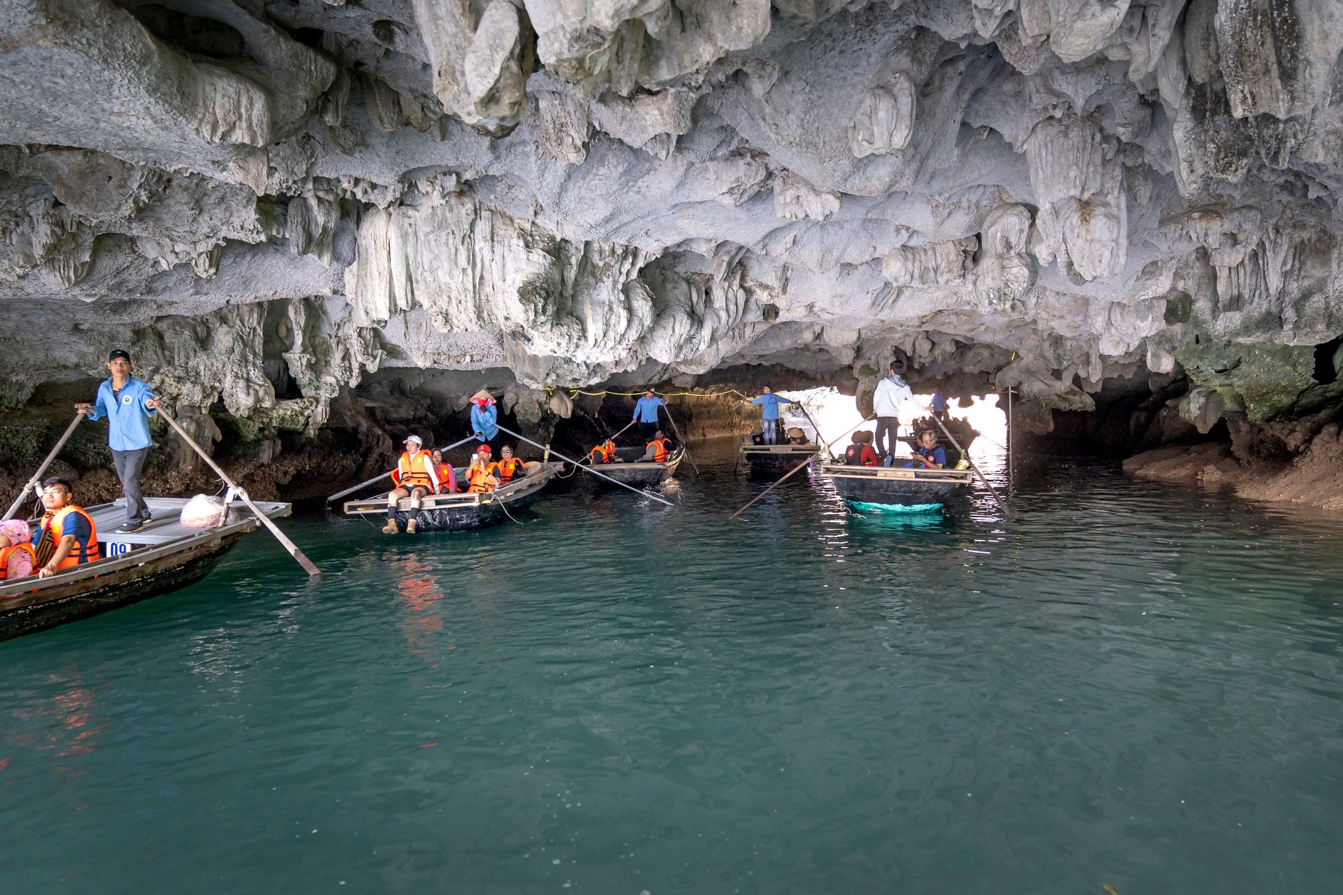 Tourists on boats explore a stunning limestone cave in Ha Long Bay, Vietnam.