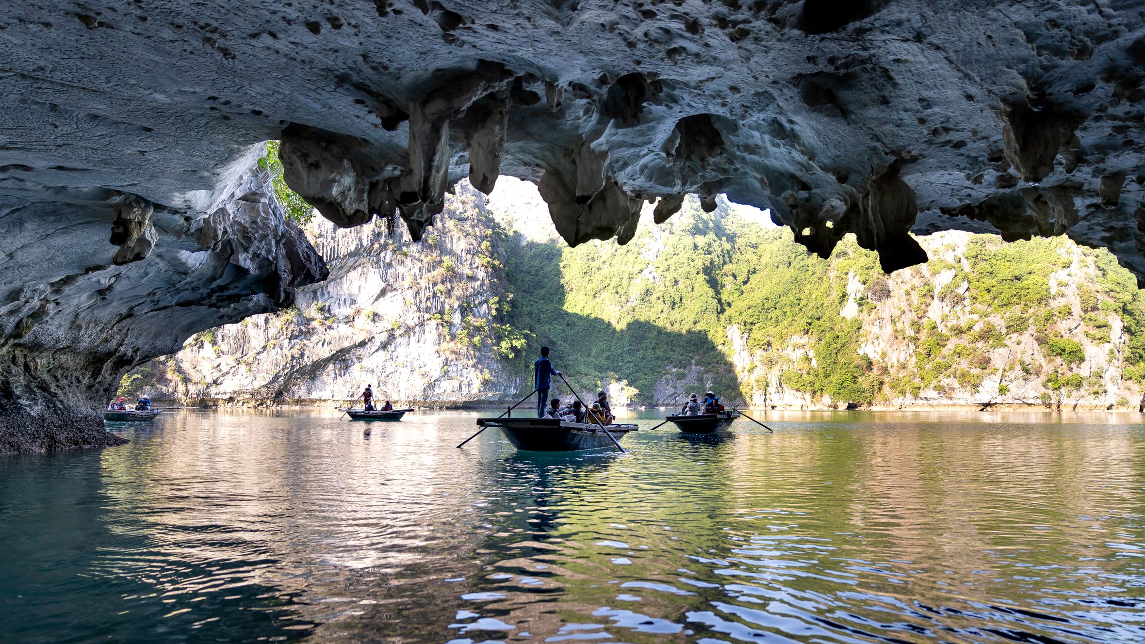 Experience the beauty of Ha Long Bay with boats navigating under a dramatic limestone cave.