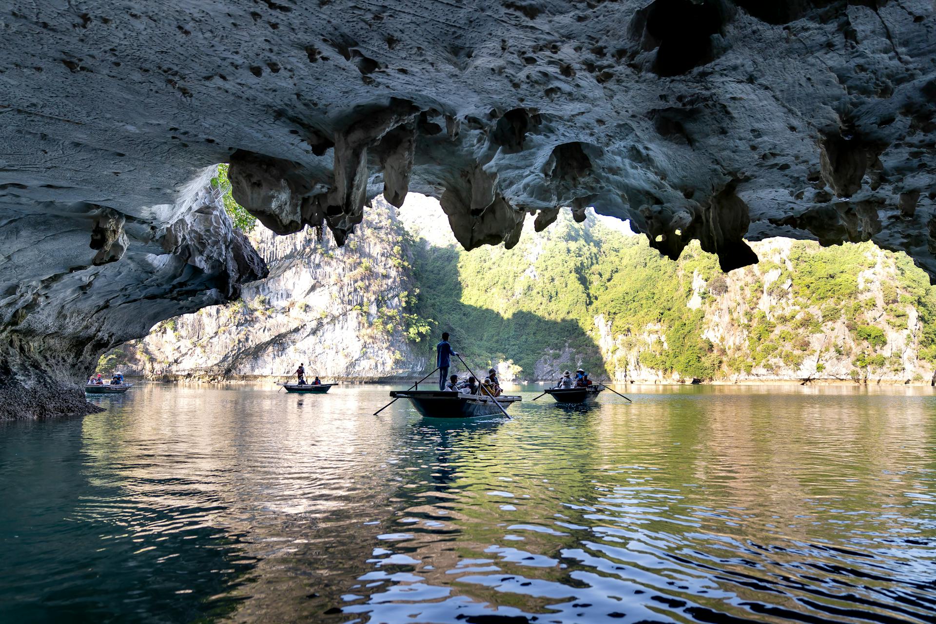 Experience the beauty of Ha Long Bay with boats navigating under a dramatic limestone cave.