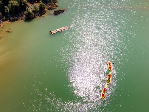 Free Drone shot of kayakers paddling on beautiful emerald green water near a coast. Stock Photo
