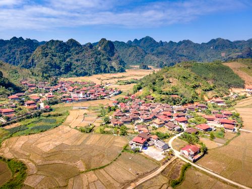 Free Explore the beauty of a picturesque rural village surrounded by fields and hills in a serene landscape. Stock Photo