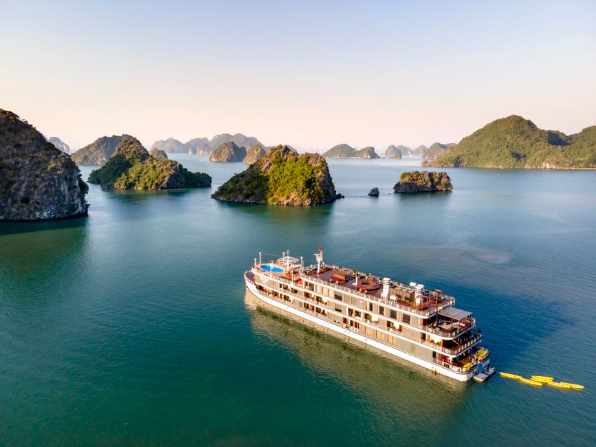 A luxury cruise ship navigates the scenic limestone islands of Halong Bay in Vietnam.