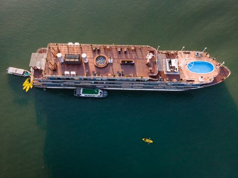 Drone shot capturing a luxurious cruise ship sailing in clear waters, complete with a pool and kayaks.