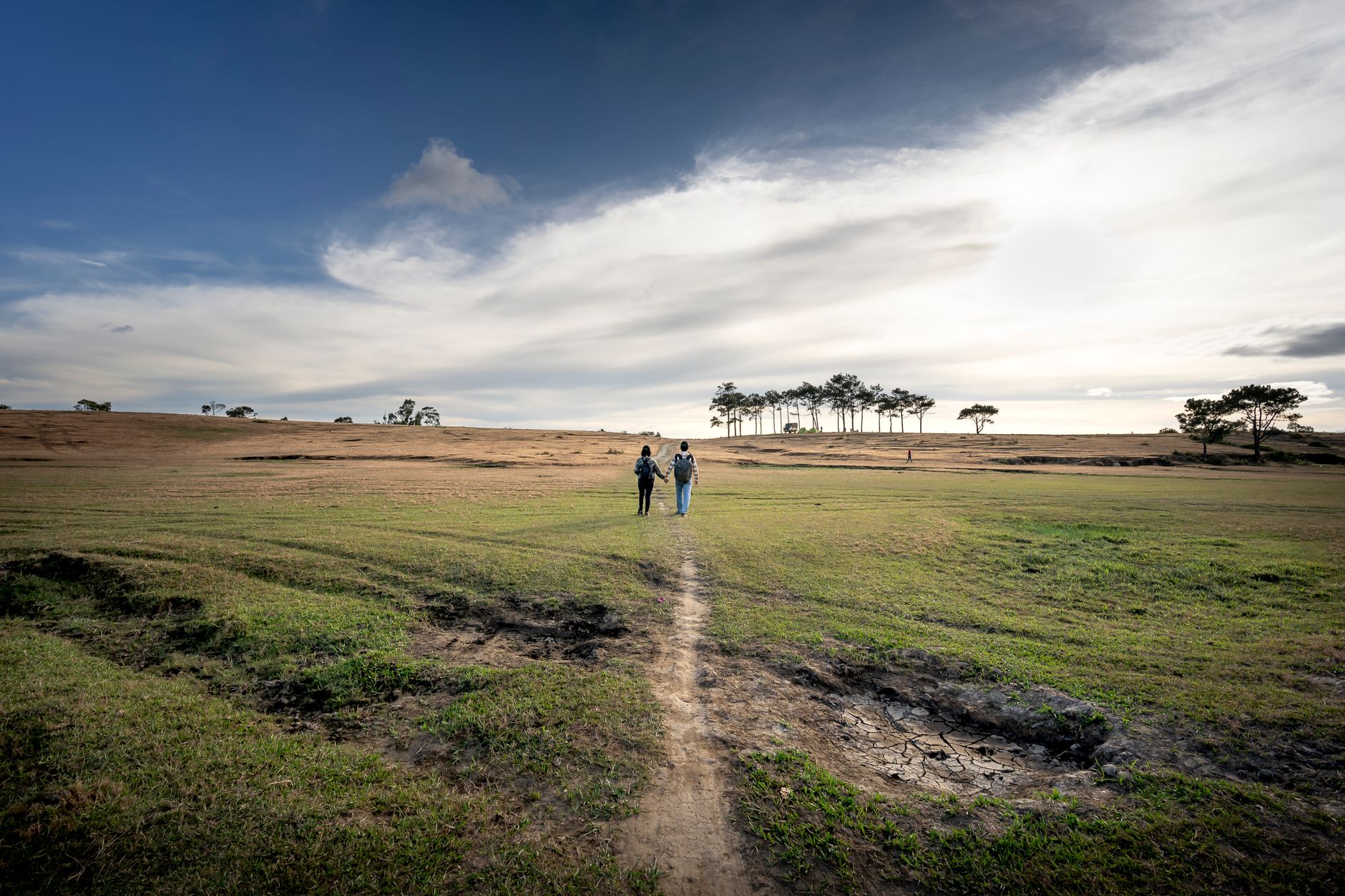 Two people walking together along a coastal path carrying day packs in morning light